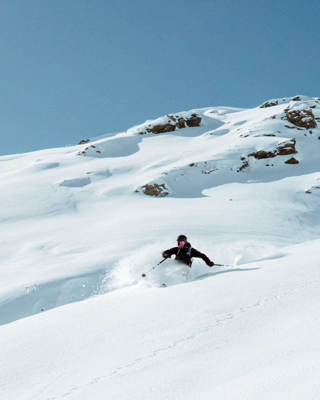 Kästle skier making a powder turn in open alpine terrain